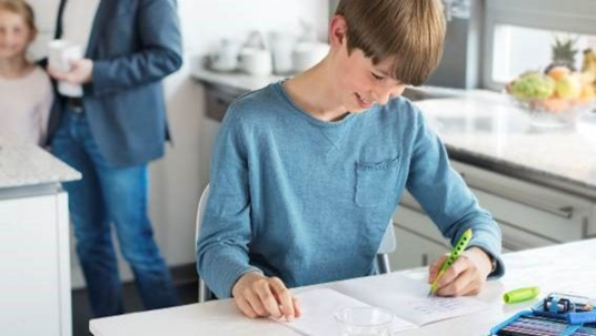 kid writing with his left hand using a green Scribolino pen by Faber-Castell 