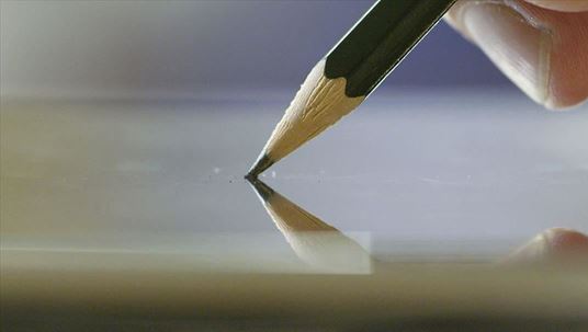 tip of a pencil getting pressed on a shiny surface